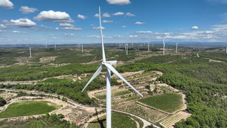 Operating-wind-turbines-with-blades-spinning-natural-rural-landscape-of-Coll-de-Moro-in-background,-Catalonia-in-Spain