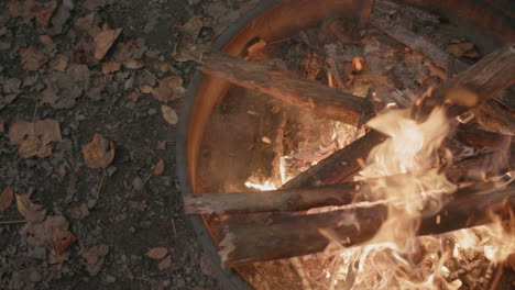 Slow-motion-footage-of-a-fire-with-the-camera-panning-across-the-flames-on-top-of-a-fire-ring-at-a-campground