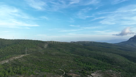 Prores-Aufnahmen-Von-Drohnen,-Die-über-Grüne-Berge-Von-Trucafort-Fliegen,-Mit-Eolic-Park-Im-Hintergrund