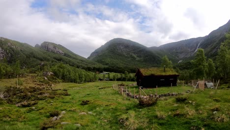 Small-cozy-outdor-shed-with-grass-roof-in-idyllic-valley-Leiro-in-Eidslandet-Norway---Timelapse-with-beautiful-clouds-and-passing-shadows-from-lush-green-Norway-mountain-landscape