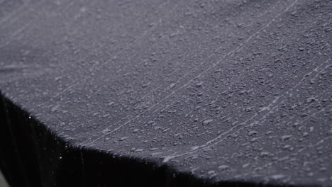 Heavy-rain-dripping-from-black-waterproof-textile.-4K