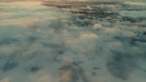Drone-flying-over-clouds-with-snowy-landscape