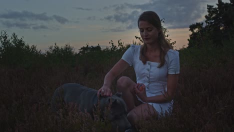 Young-woman-petting-her-dog-in-a-heather-field