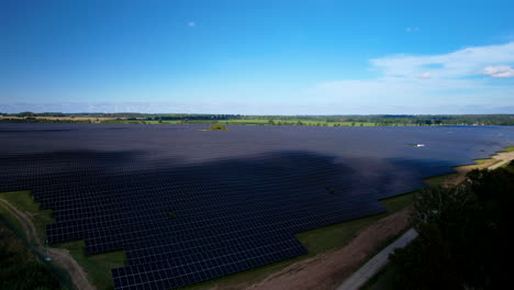 Solar-Panels-Farm-Field-Of-Green-Renewable-Energy---Ascending-aerial-view-during-blue-sky-and-sunlight
