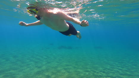 Ein-Junger-Taucher-Schwimmt-Auf-Der-Oberfläche-Des-Mittelmeers,-In-Der-Nähe-Eines-Strandes-Auf-Einer-Griechischen-Insel,-Unterwasseransicht