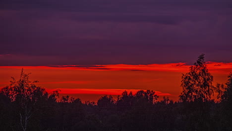 Time-lapse-of-reddish-cloudy-sunset-over-vegetated-place