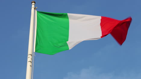 Low-angle-view-of-Italian-flag-blowing-in-wind-against-clear-blue-sky