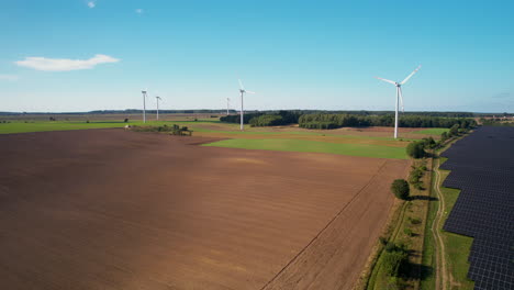 Aerial-backwards-shot-over-farm-field,solar-panels-and-wind-turbines,4k
