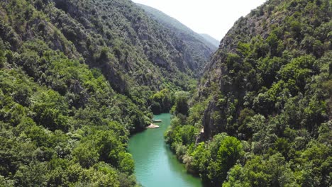 Aerial-dolly-in-through-Matka-Gorge-and-forest-with-a-river-flowing-through-it-at-sunlight