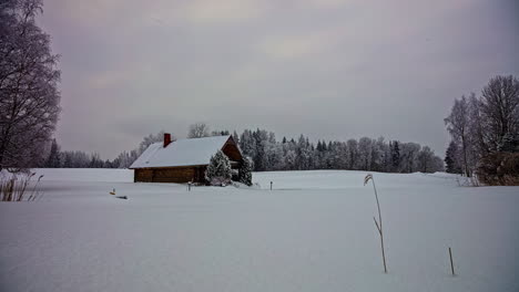 Winter-landscape,-Isolated-wooden-cottage-on-Snowy-meadow,-Forest-trees-in-Background---Time-Lapse