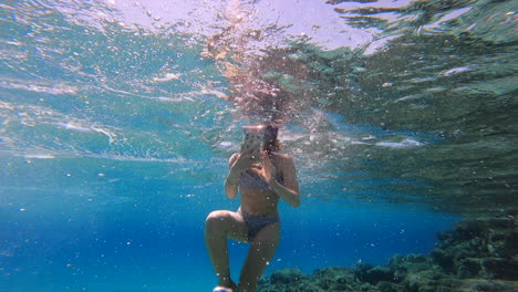 A-young-girl-films-with-her-phone-underwater-with-all-the-scuba-diving-equipment,-Greece