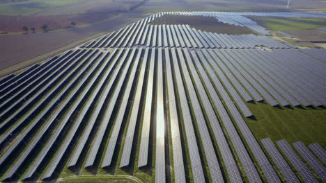 Sun-reflection-in-units-of-sustainable-solar-farm-field-during-bright-sunny-day-in-rural-area---aerial-orbit-shot