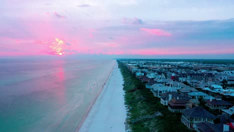 Drone-view-flying-down-the-beach-in-Rosemary-Florida-with-some-birds-flying-in-front-of-the-camera-during-golden-hour-sunset