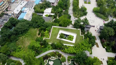 Aerial-cinematic-bird's-eye-view-with-forward-dolly-of-a-pond-on-a-sunny-afternoon-at-Huancui-lou-park,-Weihai-city,-China