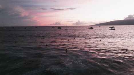 Surfers-enjoying-a-pink-sunset-sky-in-West-Maui,-Hawaii