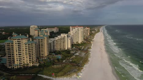 Flying-down-the-white-sand-beach-of-San-Destin-FL-during-golden-hour-with-some-dark-clouds-in-the-sky