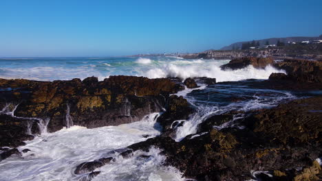 Zeitlupenantenne-Einer-Welle,-Die-über-Schroffe-Felsen-An-Der-Küste-Bricht