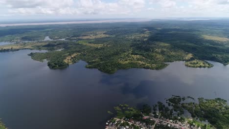 Drone-Captura-El-Río-Amazonas-Que-Fluye-Cerca-De-La-Ciudad-De-Parintins,-Brasi-Y-La-Ciudad-Que-Se-Asienta-En-El-Borde