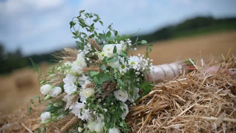 A-white-wedding-bouquet-on-a-hay-bale-sways-in-the-wind