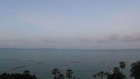 Aerial-timelapse-of-a-hazy-ocean-sunrise-view-with-passing-clouds-overlooking-the-Gulf-of-Thailand,-Pattaya,-Thailand