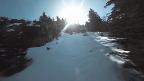 Low-cinematic-FPV-drone-flying-up-the-side-of-a-snowy-mountain