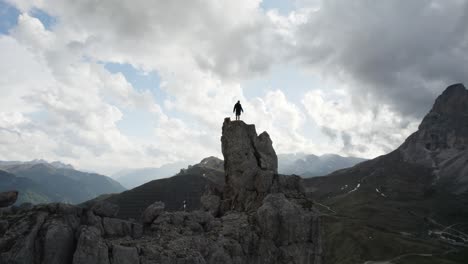 Orbit-Drone-shot-of-a-person-on-top-of-the-mountain-at-Passo-Sella-in-Val-Gardena-Italy