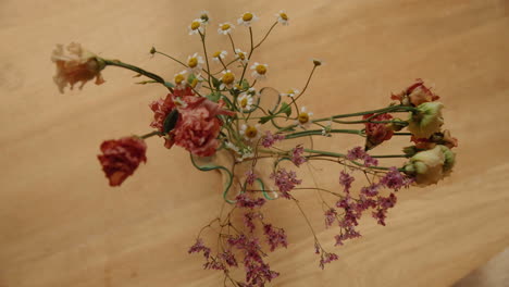 Top-Down-Shot-of-flowers-in-a-vase-standing-on-wooden-table