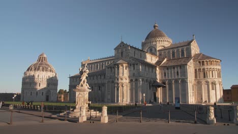 Establishment-shot-of-square-of-pisa-with-leaning-tower,-cathedral,-dome-and-movement-to-left-during-the-morning-with-golden-hour