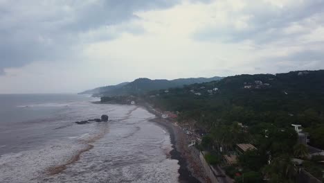 Popular-surf-spot,-El-Tunco-beach-in-El-Salvador,-during-an-overcast-and-cloudy-day---Aerial-footage---Dolly-in