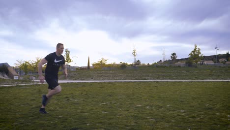 Panning-shot-of-a-tall-athletic-man-running-across-a-grass-field