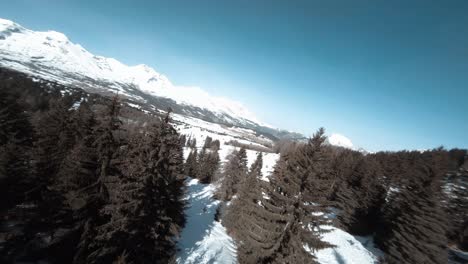 Filmisches-FPV,-Das-Entlang-Eines-Schneebedeckten-Bergrückens-Gedreht-Wurde-Und-Dann-Zwischen-Bäumen-Abstieg