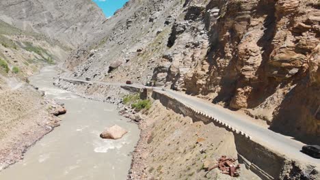 Traffic-crossing-by-the-canyon-in-between-the-mighty-mountains-of-the-Lahaul,-Himachal-Pradesh