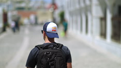 Following-a-man-with-a-backpack,-walking-on-a-public-road