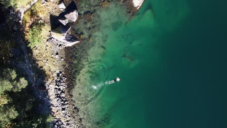 Eine-Aufnahme-Von-Oben-Nach-Unten-Eines-Mannes,-Der-Im-Wunderschönen-Türkisfarbenen-Wasser-Eines-Norwegischen-Fjords-Im-Simadal-Tal-Schwimmt
