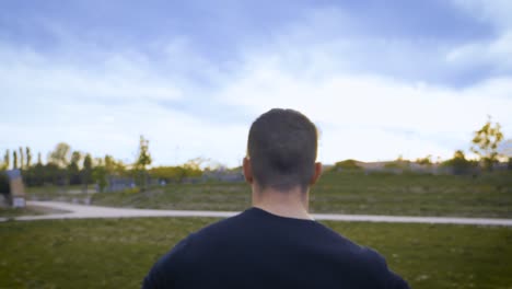 Slowmotion-tracking-shot-of-an-athletic-man-running-across-a-grass-patch