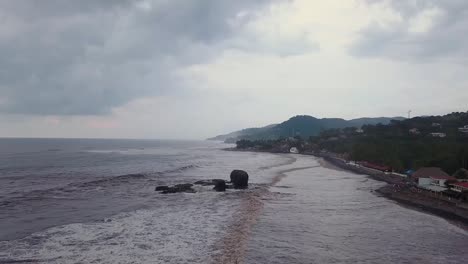 Popular-surf-spot,-El-Tunco-beach-in-El-Salvador,-during-an-overcast-and-cloudy-day---Aerial-footage---Dolly-out