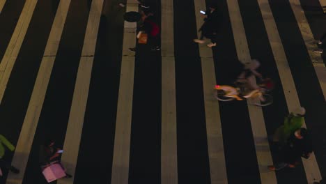 Top-down-shot-of-pedestrian-crossing-with-people-walking-over-at-night-â€“-medium-shot