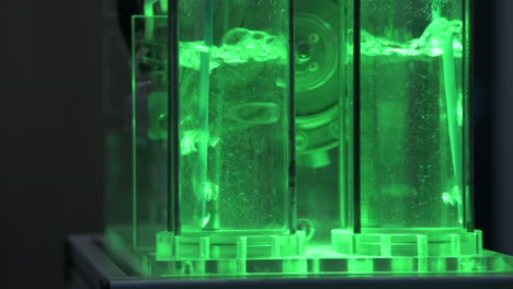 Hydrogen-gas-bubbles-in-tubes-with-water-in-a-electrolyzer-demonstrator,-green-light,-slow-motion-2