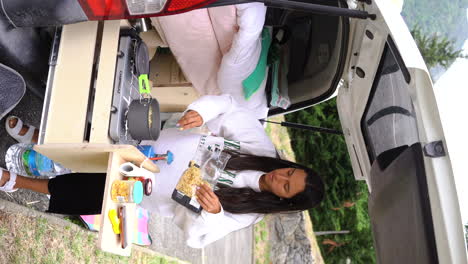 VERTICAL-of-mixed-race-young-woman-clocking-dinner-in-her-camper-car-van