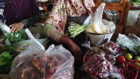 The-merchant-puts-his-wares-into-a-plastic-bag-while-counting-the-total-purchases-and-then-giving-it-to-the-buyer