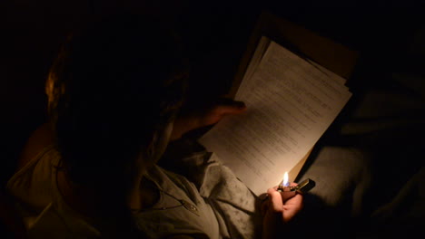 Young-soldier-lighting-a-lighter-to-read-a-letter-while-in-bed