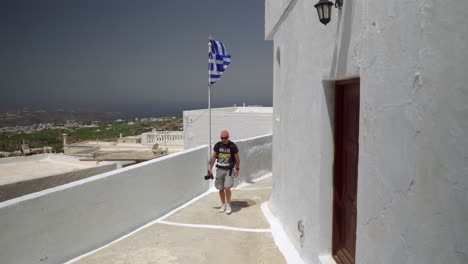 One-man-holding-a-camera-walks-down-an-alley-on-a-Greek-island