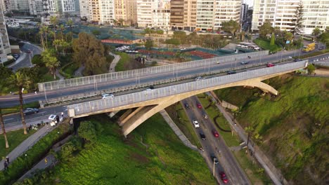 Drone-4k-of-a-bridge-with-cars-diriving-on-it,-another-street-below-the-bridge-in-between-green-grassy-hills