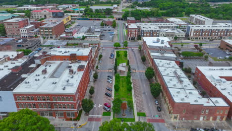 Aerial-hyperlapse-captured-in-June-2022-above-urban-traffic-on-Poplar-Street-surrounded-by-historic-buildings-in-Macon,-GA-towards-train-bridge-at-end-of-clip