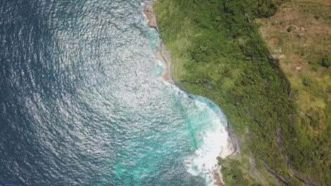 Aerial-straight-down:-Green-jungle-cliffs-protect-warm-turquoise-water