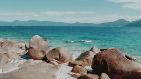 Schöner-Strand-In-Australien-Mit-Kristallklarem-Blauem-Wasser-Und-Braunen-Felsen-Auf-Weißem-Sand