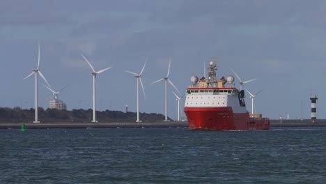 Commercial-ship-moving-up-waterway-with-wind-turbines-in-the-background