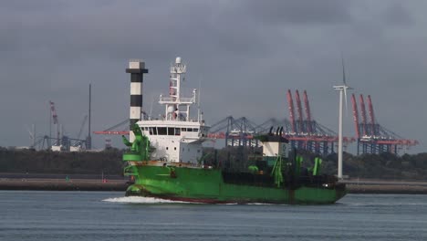 Schiff-Unterwegs-Mit-Hafenkränen-Und-Windkraftanlage-Im-Hintergrund