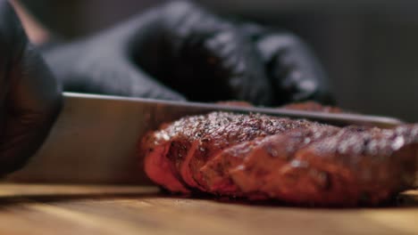 A-knife-cutting-into-a-steak-in-trips-on-a-cutting-board-at-a-fancy-gourmet-restaurant