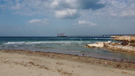 Luftaufnahme-Im-Tiefflug-über-Den-Strand-In-Richtung-Hadera-Hafen-Im-Sonnigen-Israel